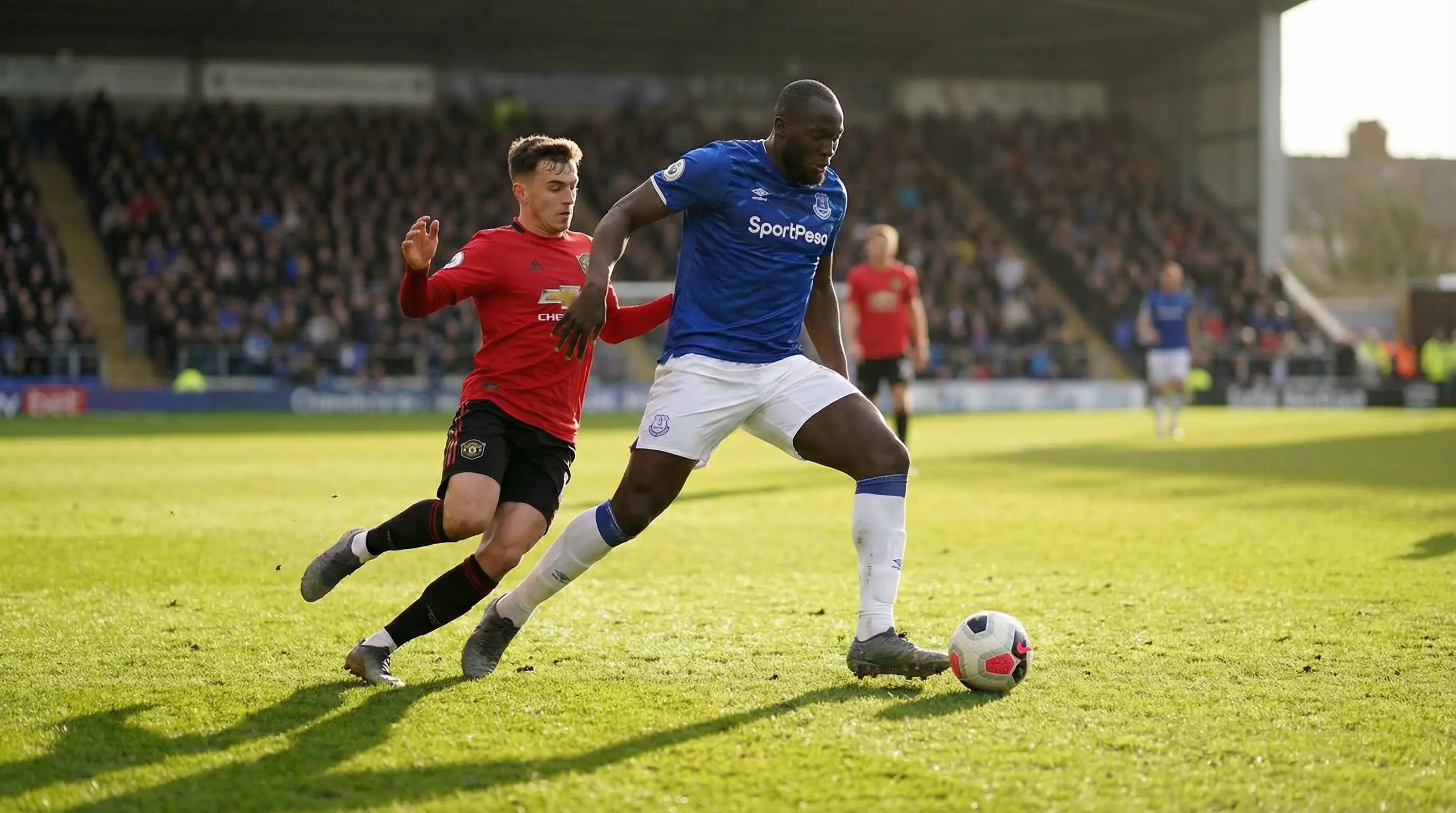 Jugadores de fútbol disputando un balón en un campo de césped durante un partido profesional